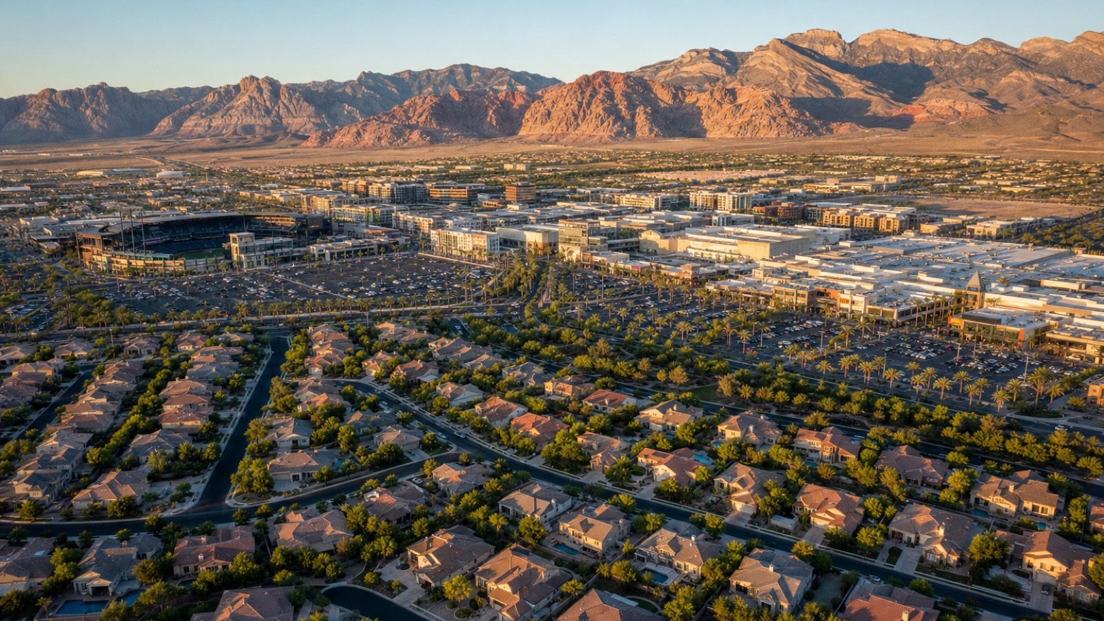 Aerial view of Las Vegas Ballpark and Downtown Summerlin's open-air retail core with City National Arena visible in the foreground and Red Rock Canyon rising in the background