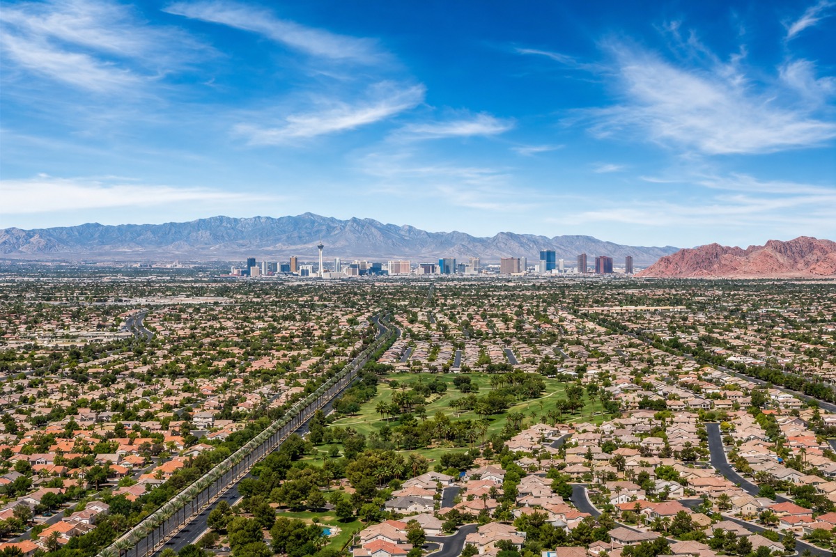 Aerial view of the Las Vegas valley at golden-hour twilight showing the Strip and surrounding suburban master plans — the territory where 18,000+ Nevada real estate licensees compete for clients