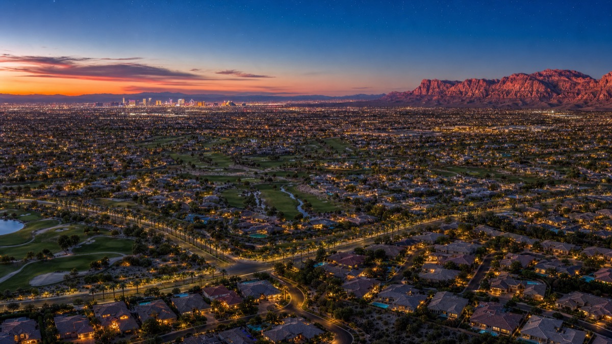 Aerial twilight view of Summerlin master plan showing residential villages and the surrounding Spring Mountains — premium territory where top Las Vegas real estate agents work guard-gated luxury inventory